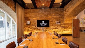 A conference room with a long wooden table, leather chairs, and a stone wall backdrop with a sign reading "Sandman Signature Sheffield Quays Hotel". - Sandman Signature Sheffield Quays Hotel (Sheffield)