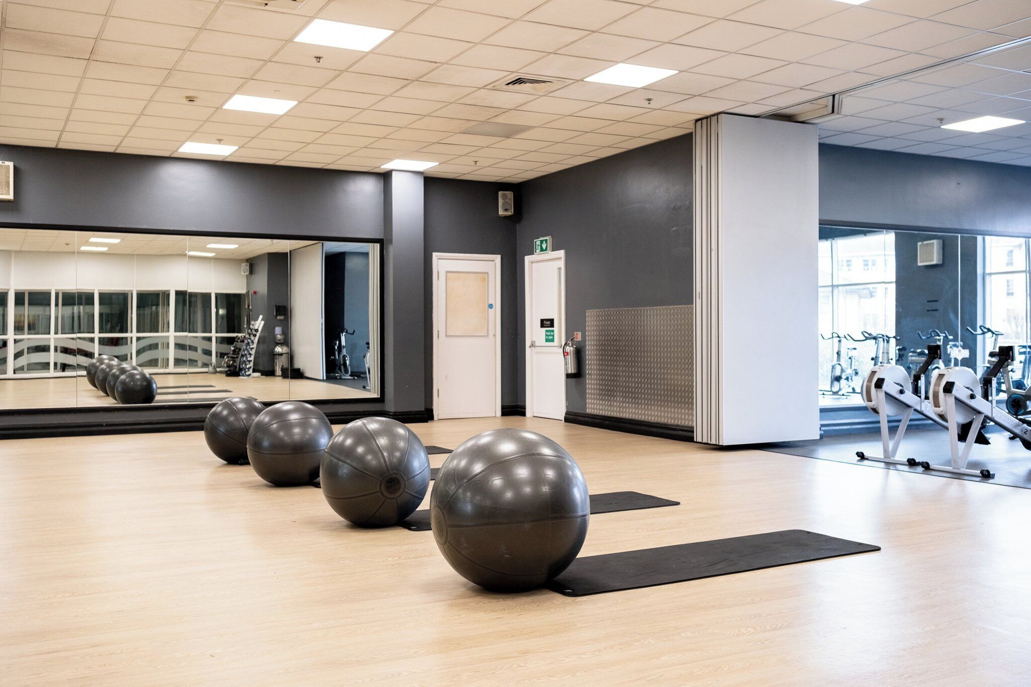 A gym with exercise balls, a mirror, and cardio equipment.