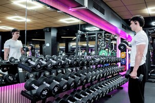 A gym with rows of dumbbells labeled with weights.