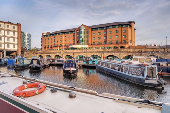 Un canal con barcos amarrados, un puente y un hotel de diseño moderno.