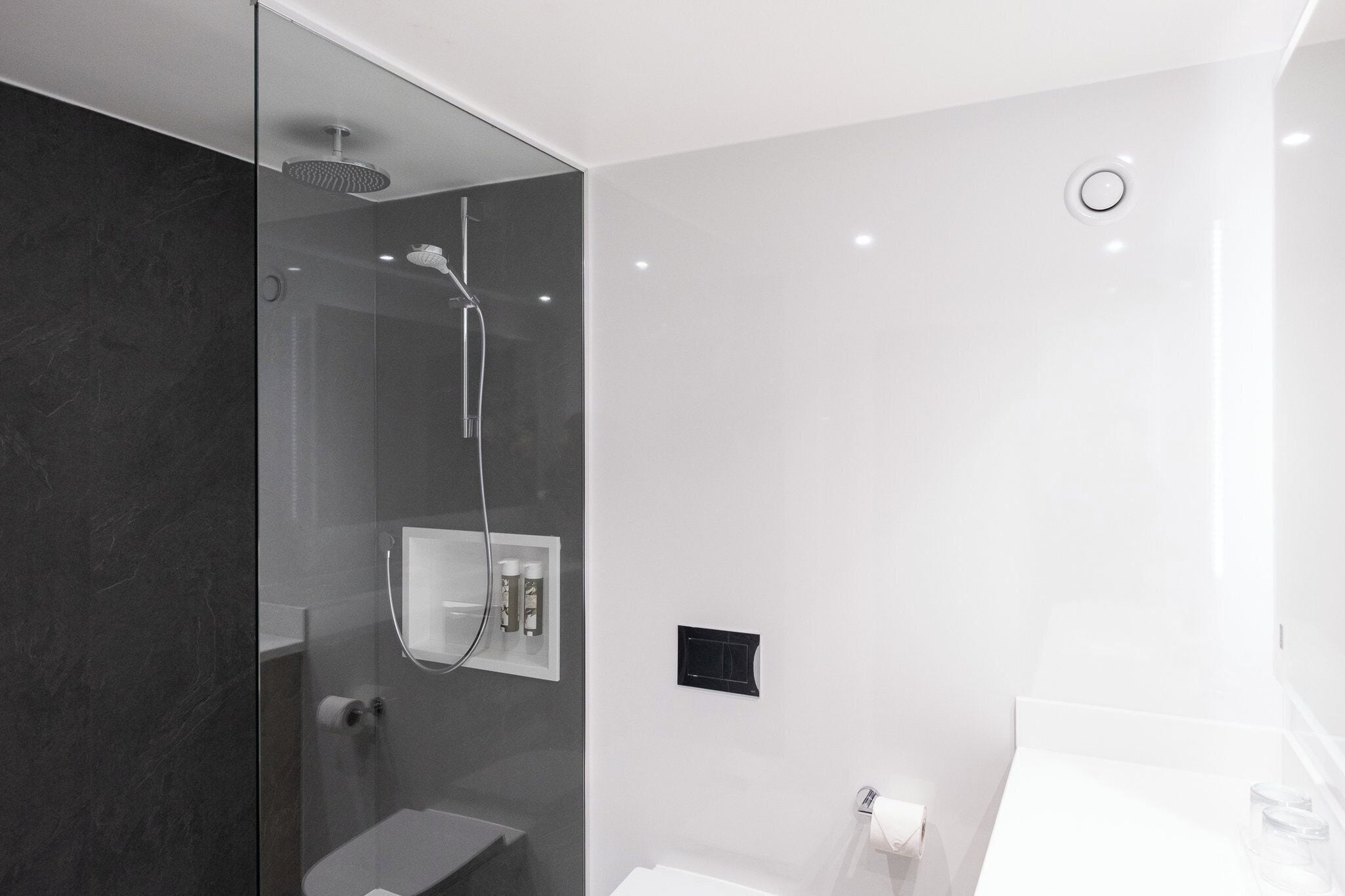 Une salle de bain moderne avec une douche à parois de verre, un lavabo blanc et des toilettes.