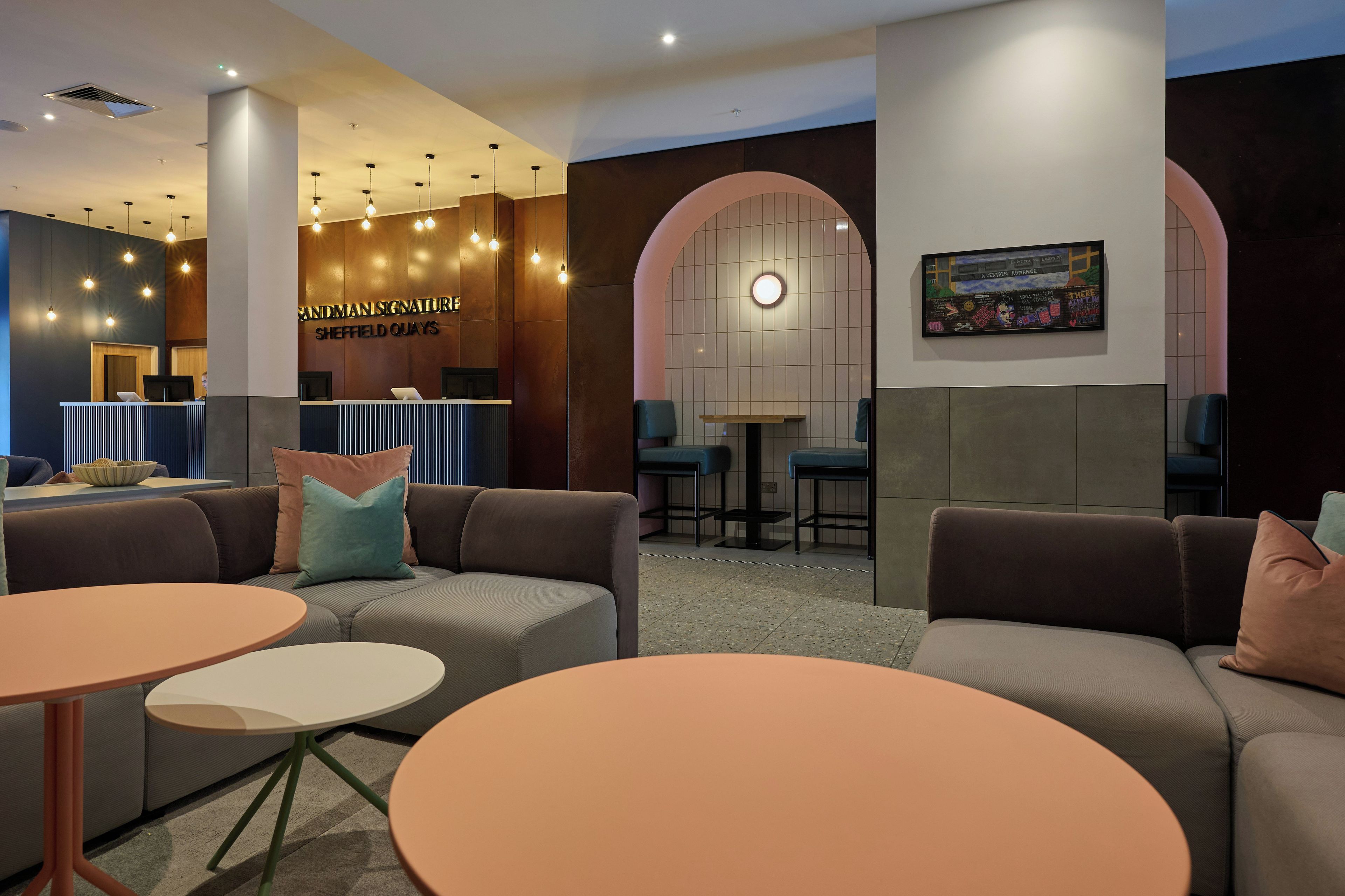 A modern lounge area with sofas, tables, and a reception desk.