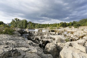 Eine felsige Landschaft mit einem Wasserfall und Bäumen im Hintergrund.