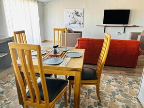Un comedor con una mesa de madera, sillas y un sofá rojo al fondo.