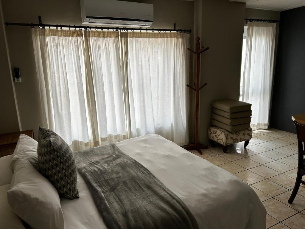 Ein Hotelzimmer mit Bett, Kleiderhaken, einem kleinen Tisch und einem Stuhl.