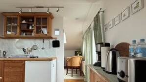 Eine kleine Küche mit Kühlschrank, Holzschränken, einer Kaffeemaschine und einem Toaster.