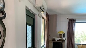 A living room with a fireplace, a small white table, and a green door. - Villa Georgia (Faistos)