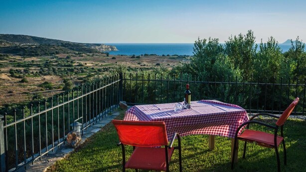 A table set outdoors with a view of the sea and hills. - Villa Georgia (Faistos)