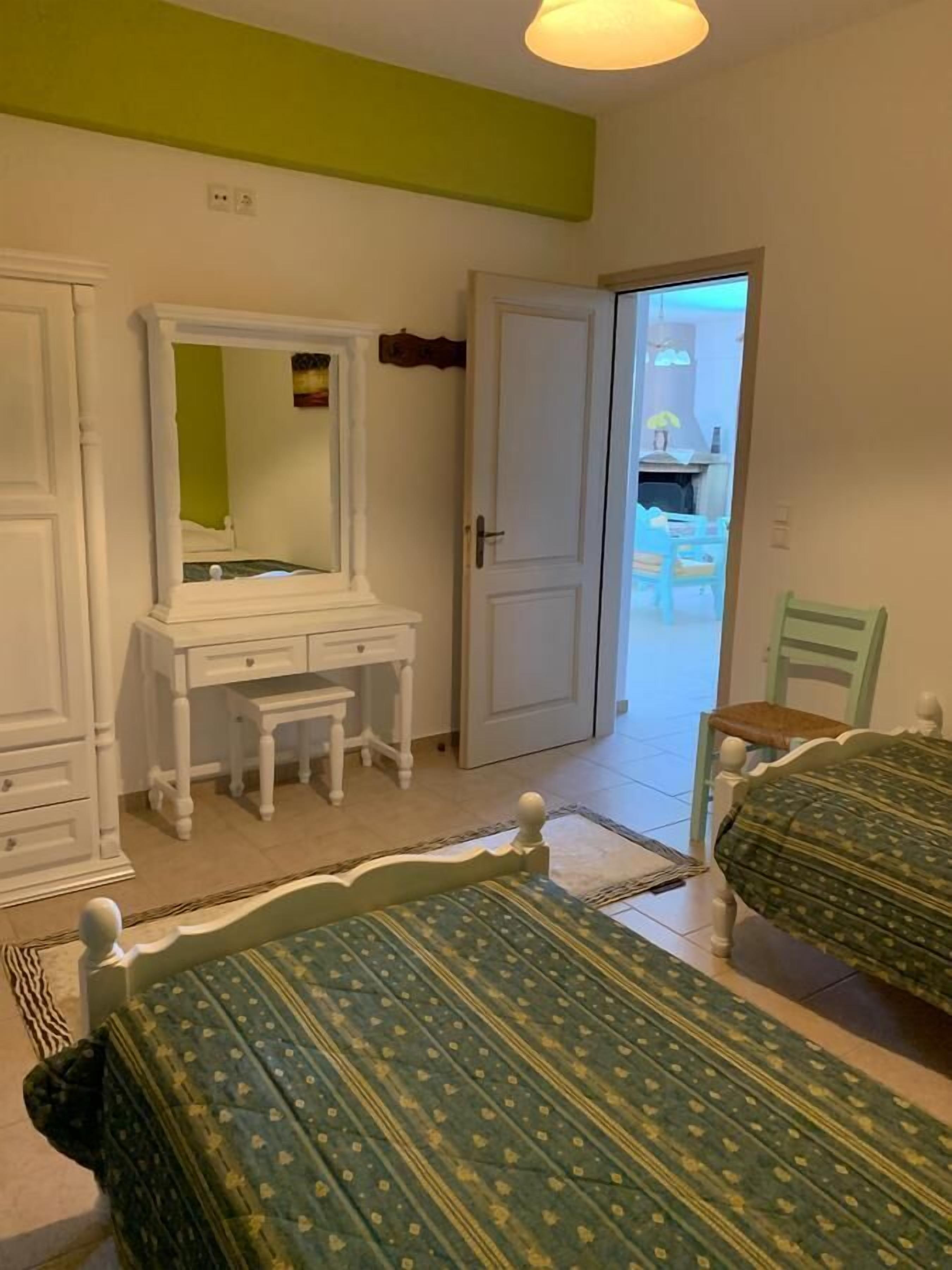 Un dormitorio con una cama, un aparador, un espejo y una puerta que da a un balcón.