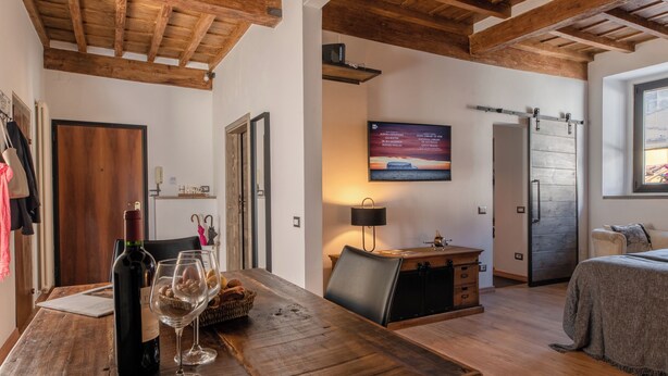 Een gezellige kamer met een houten eettafel, een bed en een aan de muur bevestigde televisie.