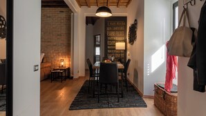 Een eetgedeelte met een houten tafel, stoelen en een zwart vloerkleed. Er is een muur met een motiverende quote in het Italiaans.