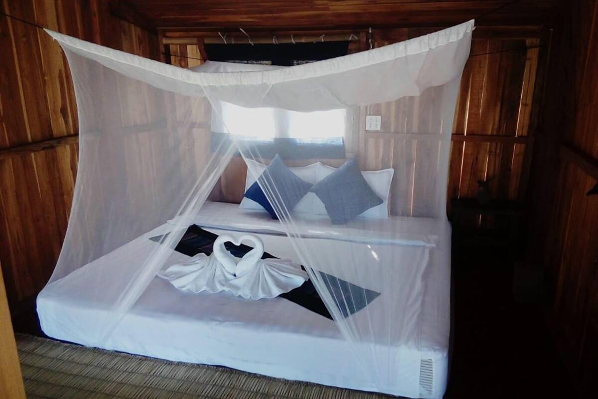 A bed with a mosquito net, pillows, and a heart-shaped decoration on the mattress.
