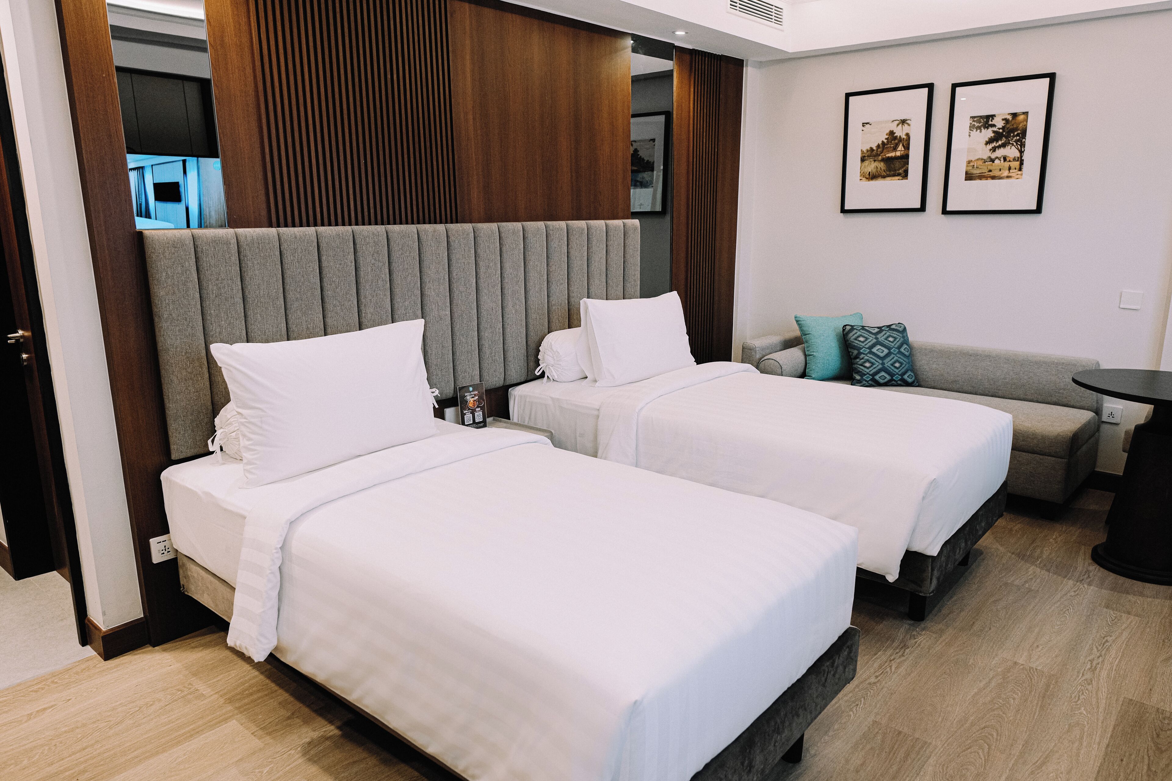 A hotel room with two beds, a sofa, and a small table.