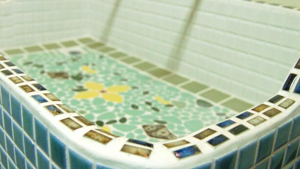 A bathroom with a blue-tiled bathtub, a white tiled wall, and a wooden door frame. - Nikko Guesthouse Sumica - Hostel (Nikko)