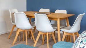 A dining table with six chairs, a wooden table top, and a blue wall in the background. - Enjoy wonderful water views from Heritage 303 (Tuncurry)
