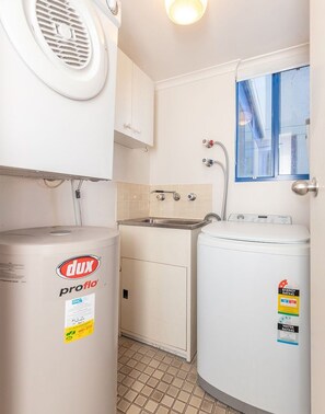 A compact kitchen with a sink, a window, and two white appliances labeled 'dux proflo'. - Enjoy wonderful water views from Heritage 303 (Tuncurry)