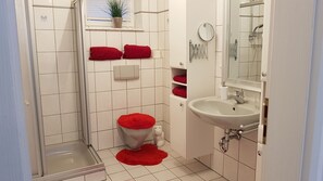 A bathroom with a shower, toilet, sink, and a mirror.