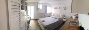 A compact bedroom with a bed, bedside table, and a small kitchenette area. - San Polo 1948 (Venice)