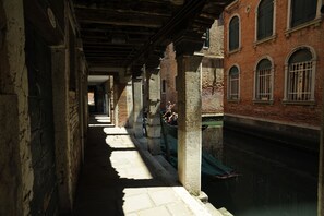 A narrow alleyway with brick buildings, a canal, and a gondola. - San Polo 1948 (Venice)