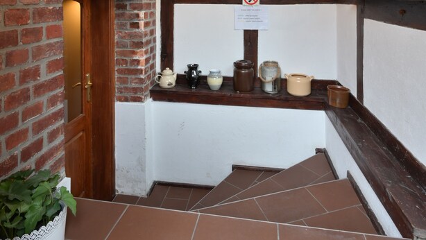 Een trap met een bakstenen muur, een houten deur en een hangende vogelkooi.