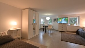 Een moderne slaapkamer met een bed, nachtkastje en een televisie op de achtergrond.