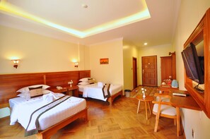 A hotel room with two beds, a desk with a chair, a television, and a small table with a vase. - Golden Classic Hotel Bagan (Nyaung-U)