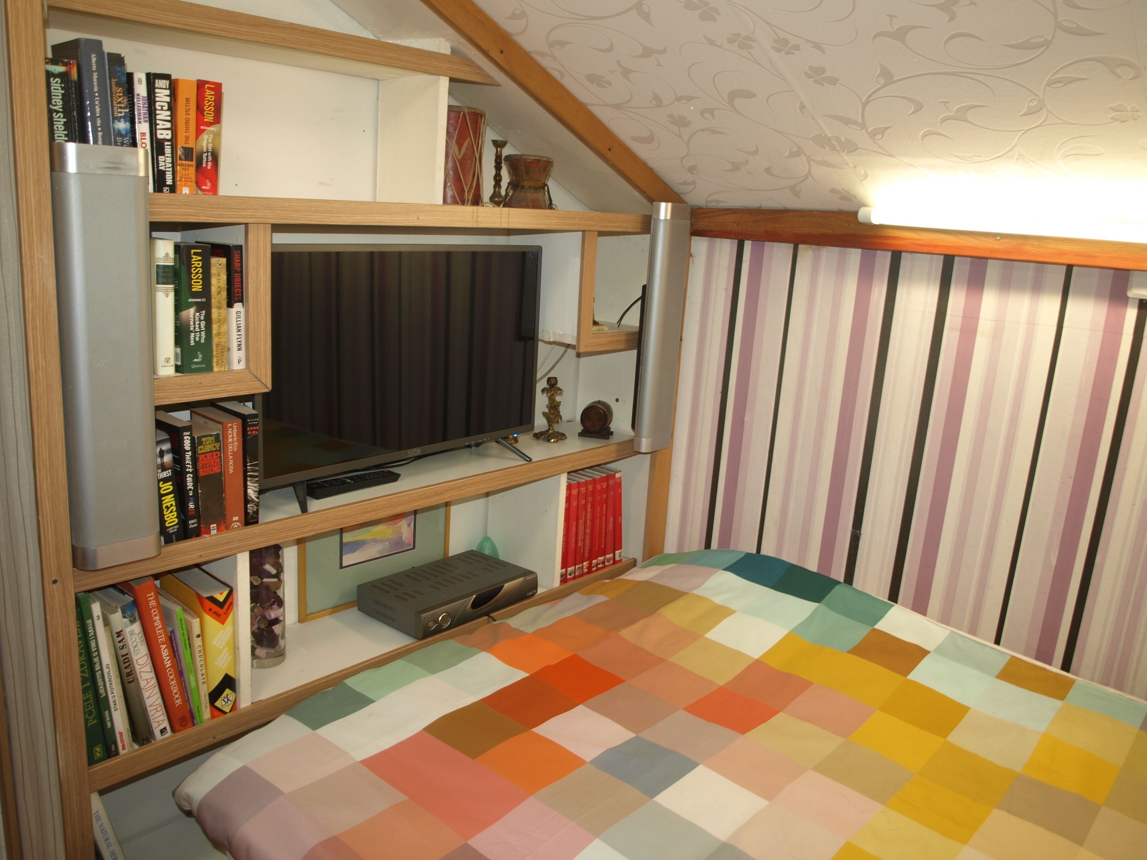 Une chambre à coucher avec un lit, une télévision et des étagères à livres.