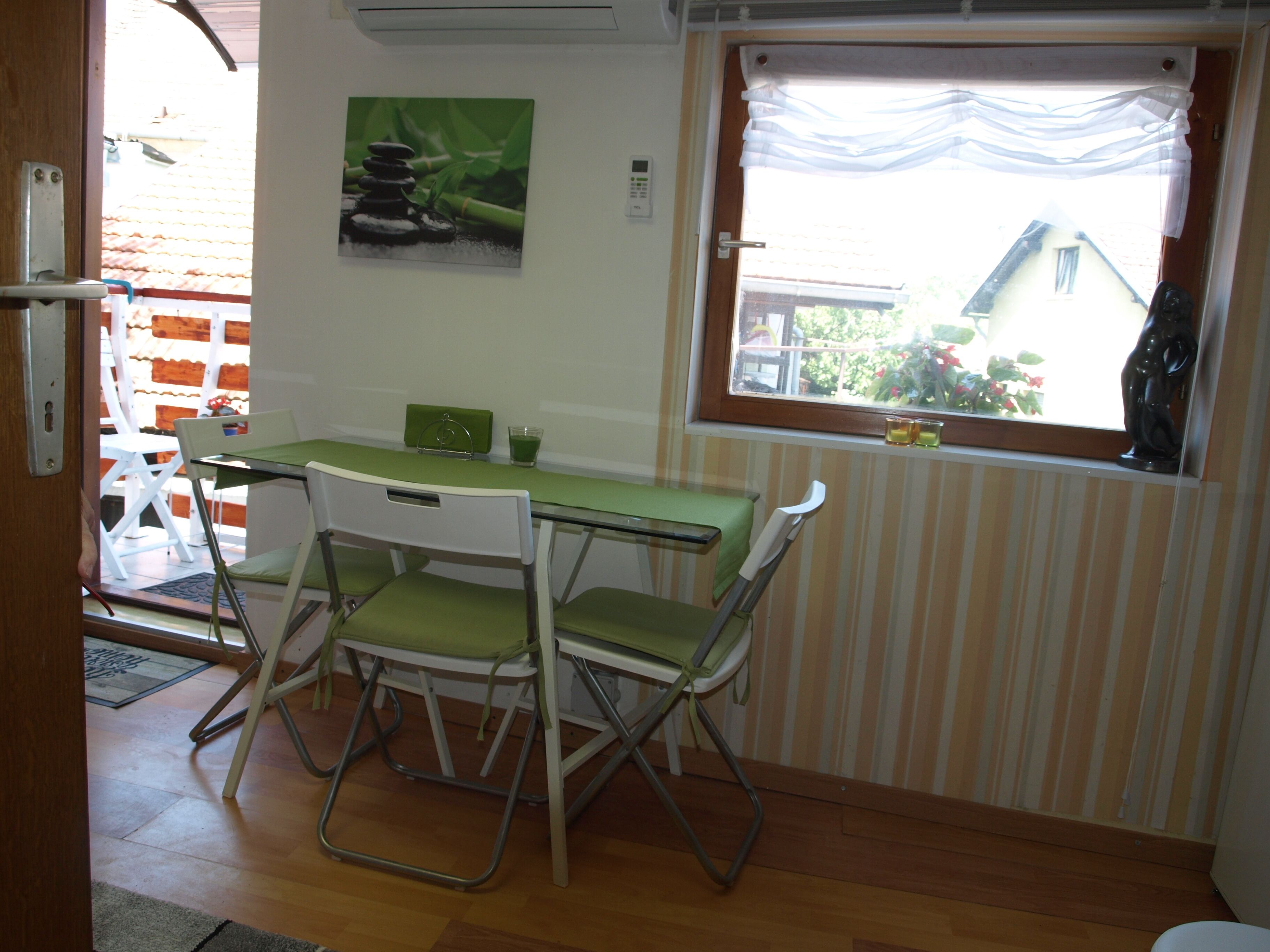 Un comedor con una mesa y sillas, una ventana con cortinas y un cuadro en la pared.