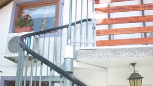 A spiral staircase with metal railings and wooden steps leading to a balcony. - STUDIO GREEN   near city center, free parking, wifi, at banks of river Sava (Zagreb)