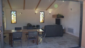 Un saló modern amb zona de menjador, amb una porta de vidre que dona a un espai exterior.