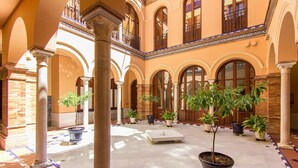 Un ampio cortile con numerosi archi, colonne e piante in vaso.