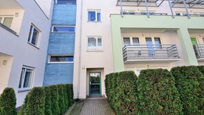 Um edifício residencial de vários andares com fachada azul e branca, uma porta verde e uma varanda com guarda-corpo de metal.