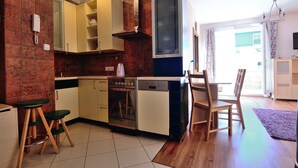 Uma cozinha compacta com forno embutido, máquina de lavar louça e um espaço de refeições de madeira.