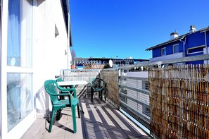 A balcony with a table and chairs, a view of the city, and a bamboo fence.