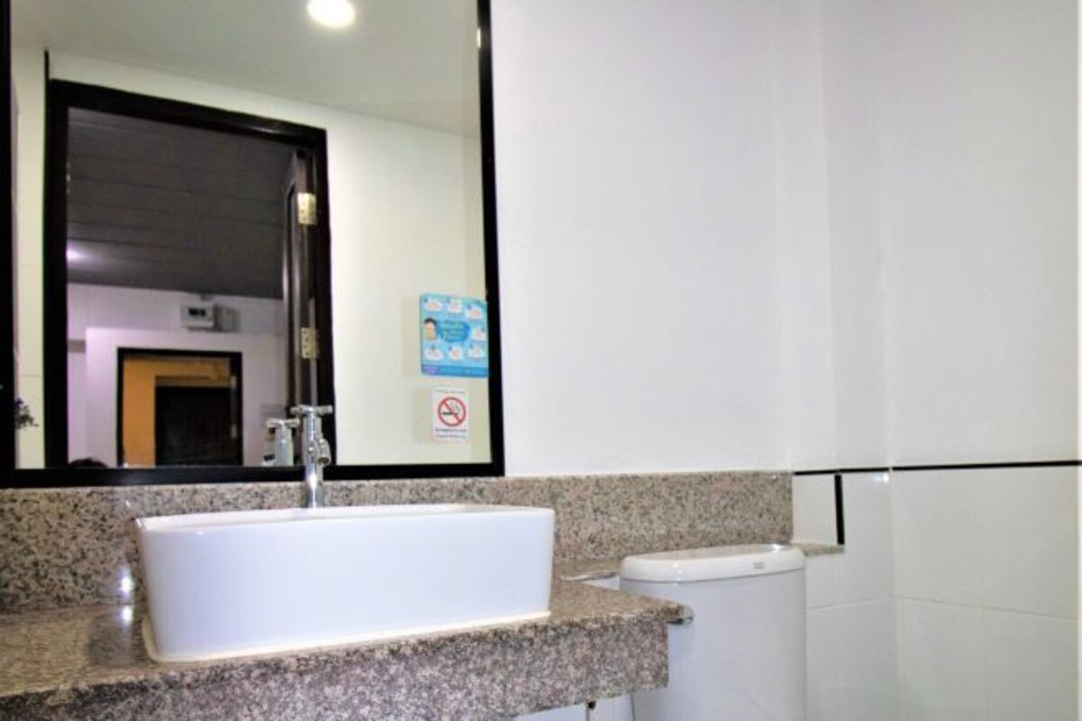 A bathroom with a white sink, a mirror, a toilet, and a sign on the wall.