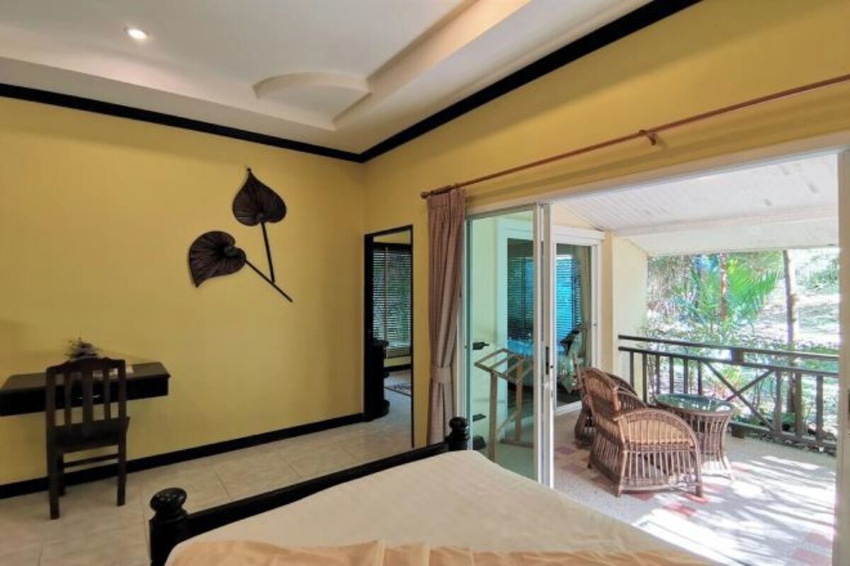 A bedroom with a bed, a desk, a chair, and a balcony with a view.
