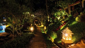 A nighttime garden pathway with illuminated lanterns and lush greenery. - Thai Modern Resort & Spa (Chalong)