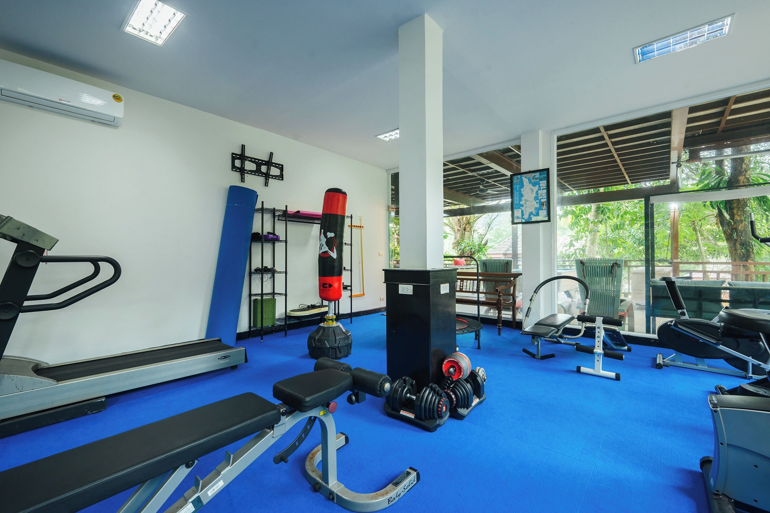 Un gimnasio con cintas de correr, bancos de pesas y un saco de boxeo.