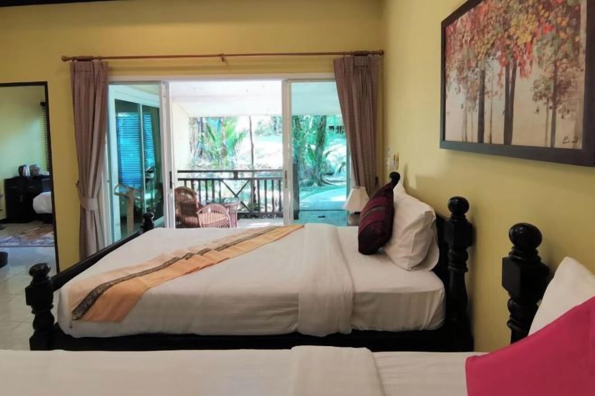 A double bed with a headboard, a nightstand, and a window with curtains.