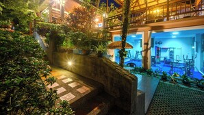 A well-lit outdoor area with a stone pathway, lush greenery, and a thatched-roof structure. - Thai Modern Resort & Spa (Chalong)