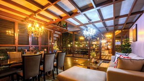 A modern interior with a dining area, sofas, and a chandelier. - Thai Modern Resort & Spa (Chalong)