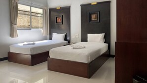 A hotel room with two beds, a window with curtains, and a wall-mounted air conditioner. - C.A.P. Mansion Hotel (Phuket)