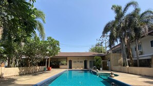 A swimming pool with a tiled deck, surrounded by palm trees and a covered seating area. - C.A.P. Mansion Hotel (Phuket)