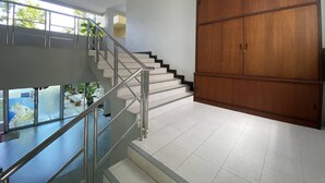 A modern interior with a staircase, glass railing, and a large wooden wardrobe. - C.A.P. Mansion Hotel (Phuket)