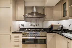 A kitchen with a stainless steel range hood, oven, and microwave.