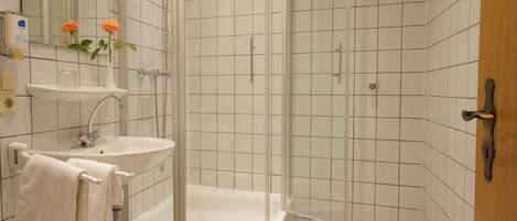Un baño con ducha de vidrio, lavamanos y espejo.