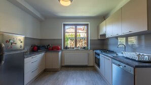 Ett modernt kök med vitvaror i rostfritt stål, ett fönster med utsikt över omgivningen och en inbyggd diskmaskin.