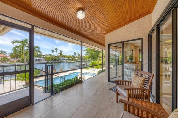 A spacious balcony with a view of a swimming pool and palm trees.