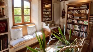 Un rincón acogedor para leer con un banco empotrado, una amplia estantería y una ventana con vistas a la vegetación.