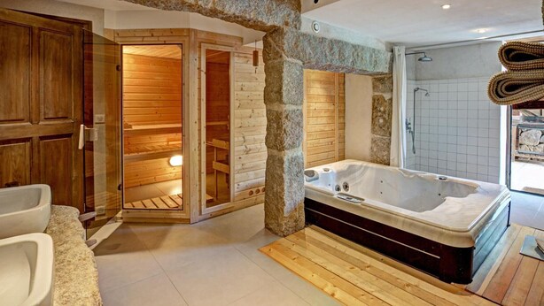 Un baño moderno con un arco de piedra, paredes de madera, una bañera grande y una zona de ducha.